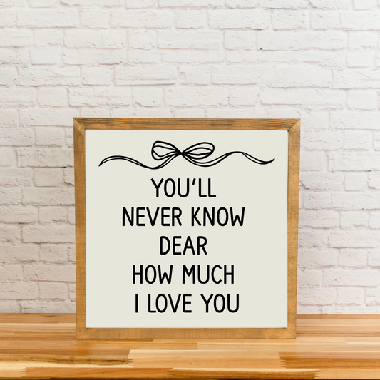Neutral nursery wall sign that says 'You'll never know dear how much I love you,' laser cut wood with a simple bow.