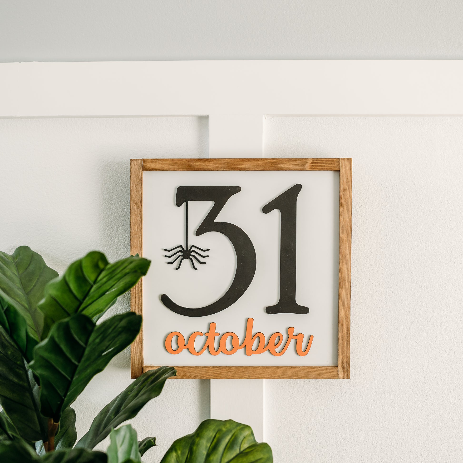 A square-shaped Halloween sign with the date '31 October' written in black, with a spider hanging from the number 1. The sign has a white background and a weathered walnut stain.